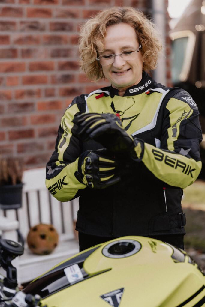 Frau in Motorradjacke zieht ihr Handschuhe an, Persnonal Brand Shooting in Borgholzhausen