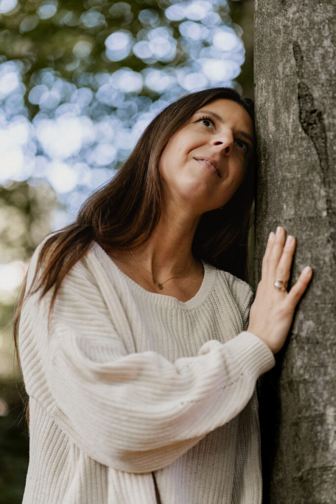 Yogalehrerin lehnt an Baum